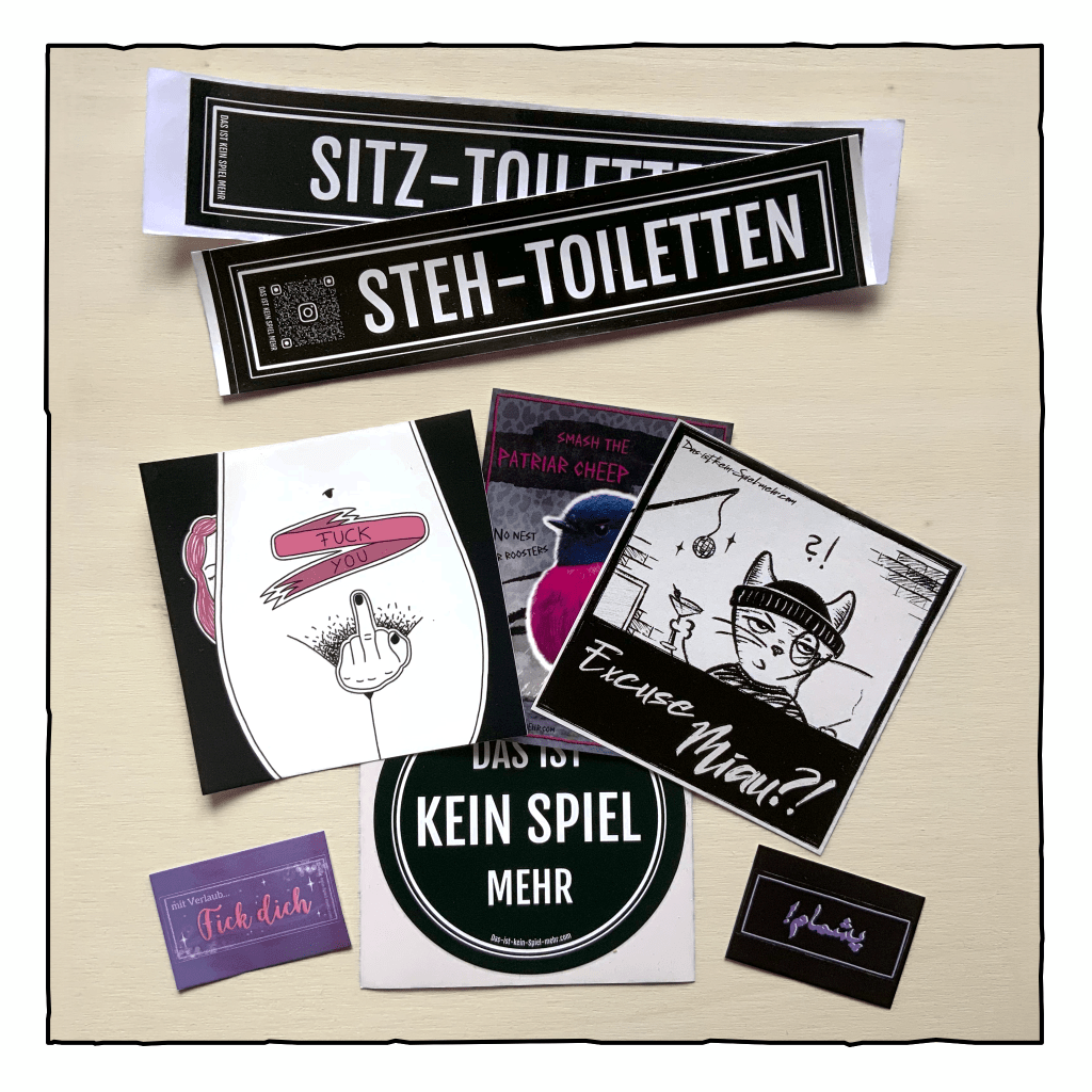 Acht Sticker liegen verteilt auf einem Holzbrett. Die meisten Sticker haben einen schwarzen Hintergrund mit weißer Schrift und Zeichnungen in pink oder lila.
