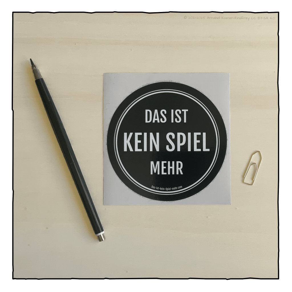 Runder Sticker auf einem Holzbrett. Auf schwarzem Hintergrund steht in weiß Das ist kein Spiel mehr.