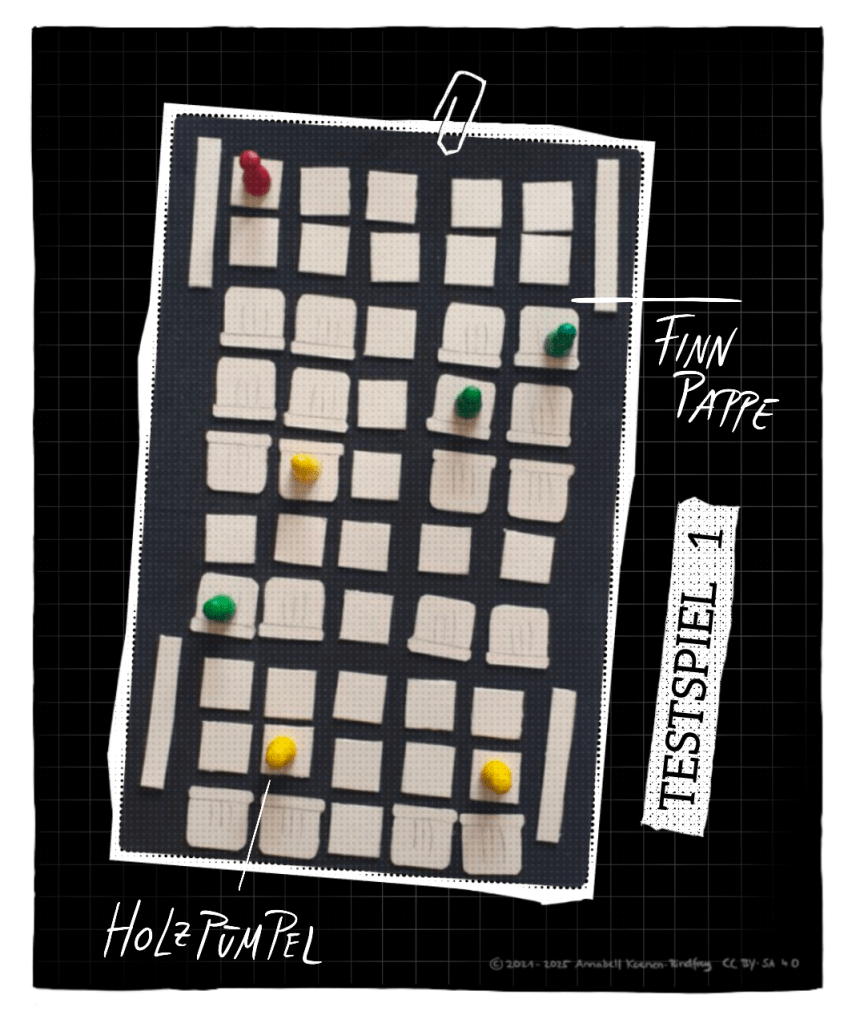 Ein Foto zeigt Papierschnipsel, die auf einem schwarzen Stück Schaumstoff angeordnet sind. Die Papierschnipsel stellen den Grundriss einer U-Bahn dar. Es gibt quadratische Schnipsel, die einen Sitz von oben zeigen. Am Rand des Bildes stellen schmale Schnipsel die Türen der Bahn dar. Auf sieben Schnipseln stehen Spielfiguren in verschiedenen Farben.